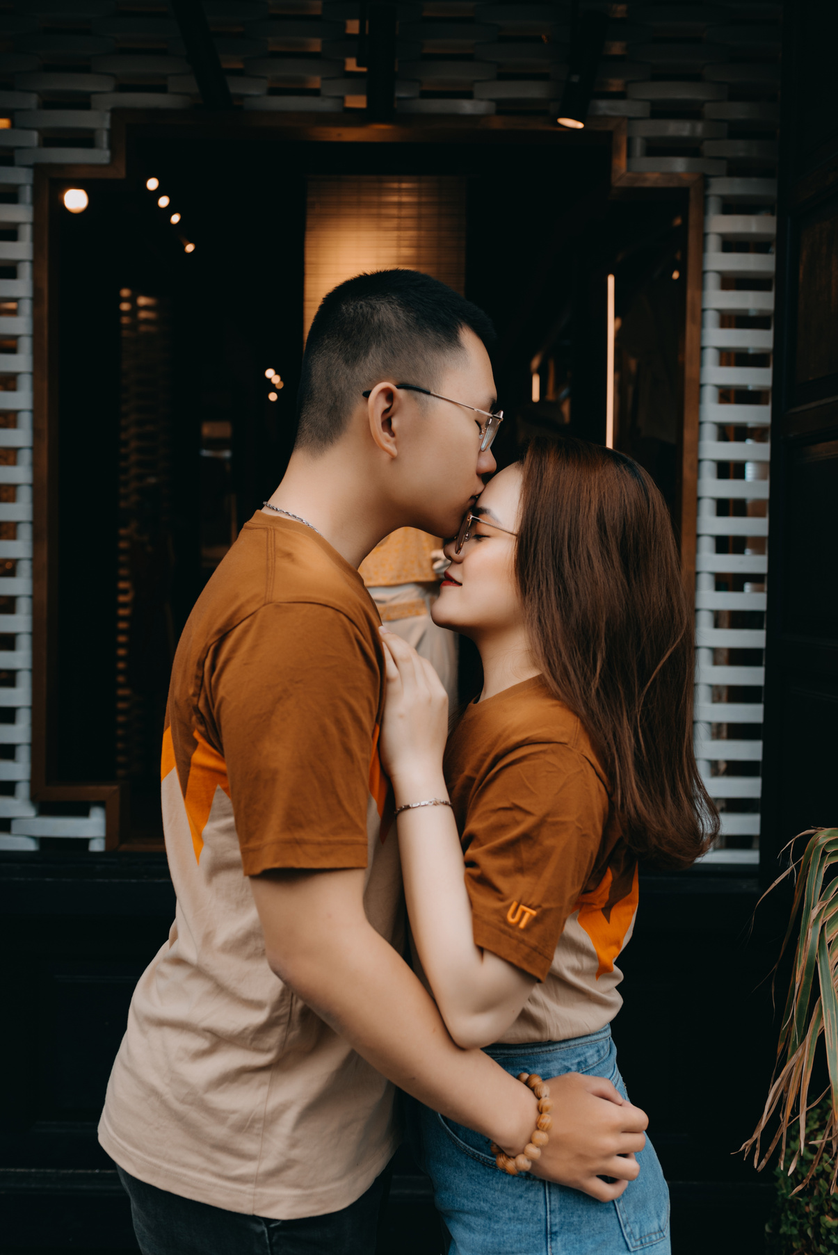 Gentle stylish Asian couple with eyes closed cuddling and kissing